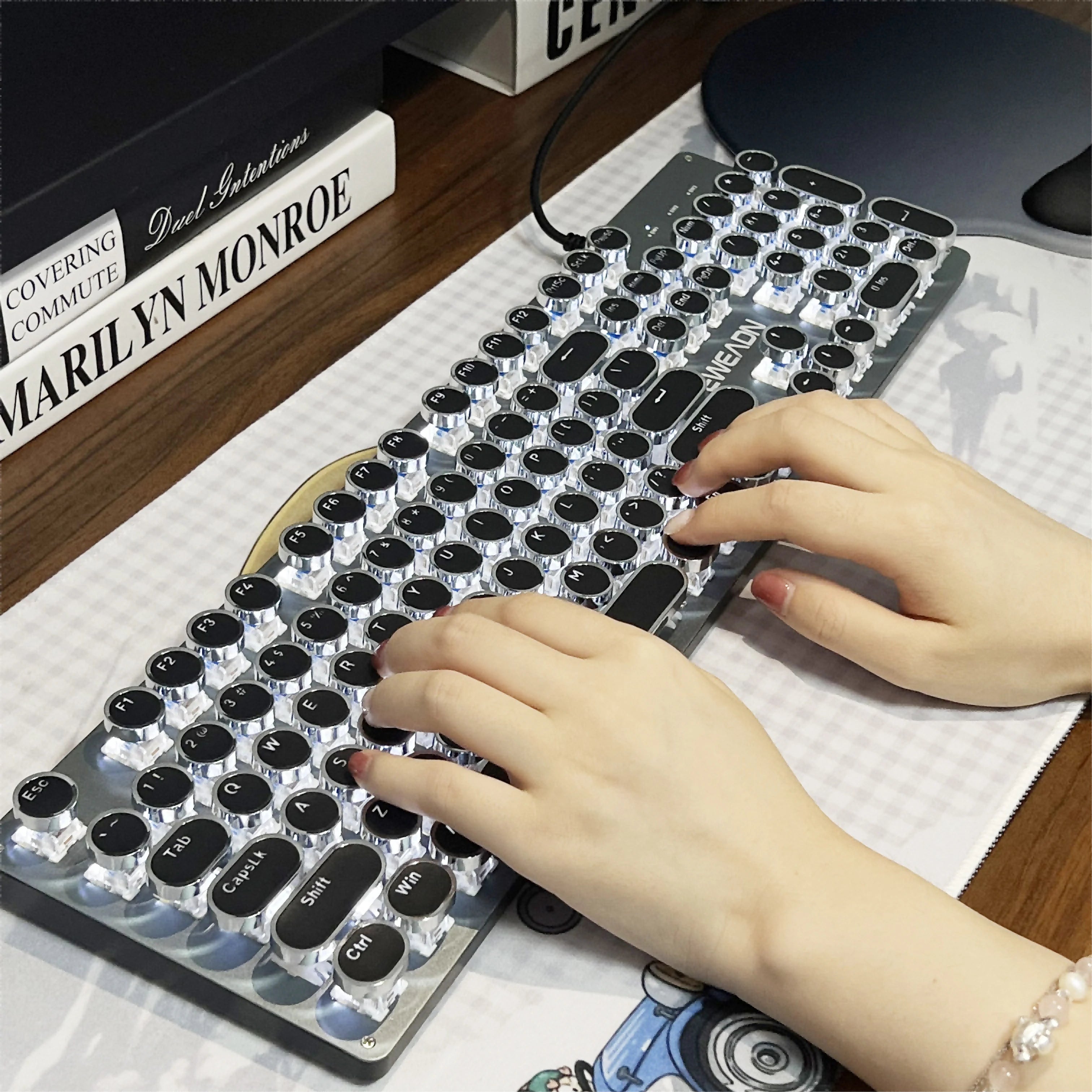 Person using a unique keyboard with decorative keys on a desk.
