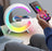 Colorful LED night light with smartphone charging pad and digital clock, held by a person.